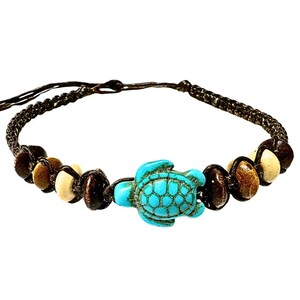 May include: A brown macrame bracelet featuring a turquoise turtle charm. The bracelet is adorned with wooden beads in shades of brown and cream. The turtle charm is a vibrant turquoise color.