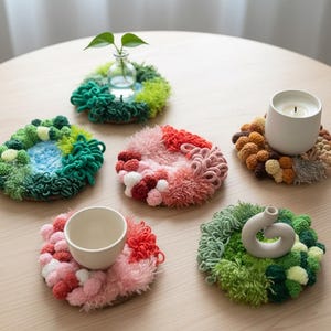 Peut inclure: Ensemble de dessous de verre faits à la main, aux couleurs vives et à la texture tissée. Chaque dessous de verre présente une palette de couleurs unique, avec des nuances de vert, rose, rouge et marron. Certains supportent des vases, une bougie et une tasse.