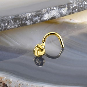 May include: Gold nose ring with a knot design. The ring is made of surgical steel and is available in a variety of sizes.