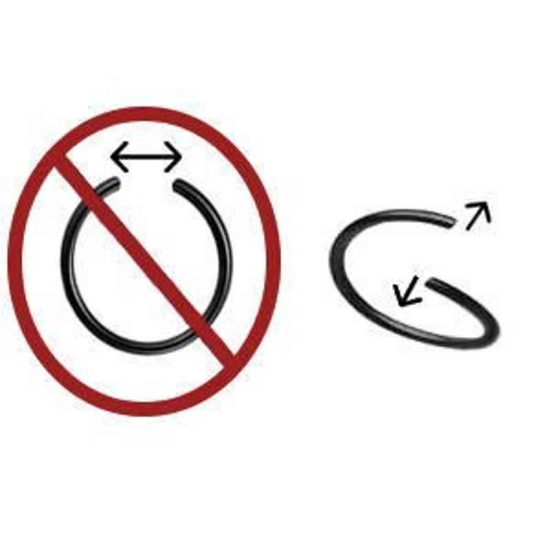 May include: Black nose ring hoop, shown in a close-up view. The hoop is open and can be worn in the nose or other body piercings. The hoop is not meant to be stretched or resized.