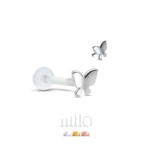 May include: A silver butterfly labret stud with a clear, flexible post. The butterfly is detailed with curved wings. Additional stud options in silver, gold, and rose gold are shown below the main image. This body jewelry is designed for lip or ear piercings.