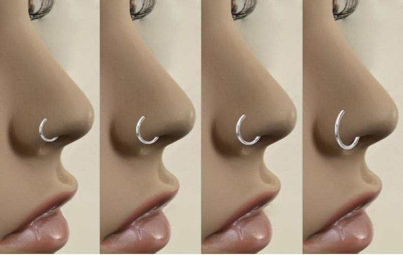 May include: Close-up of four different nose rings. Each ring is a simple silver hoop.