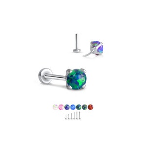 Puede incluir: Un piercing de cuerpo de plata con una piedra redonda de ópalo verde. El piercing se muestra con una variedad de otros colores de piedras preciosas.