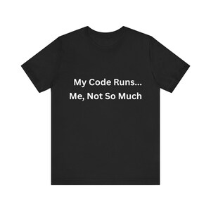 May include: Black t-shirt featuring the white text "My Code Runs... Me, Not So Much". The crew neck t-shirt is made of a soft fabric. The text is centrally positioned on the front of the garment.