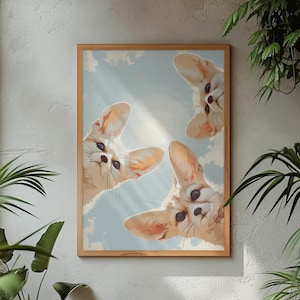 Op de afbeelding: Een rechthoekige wandkunstprint in een lichthouten lijst met drie woestijnvossen met grote oren die naar beneden kijken vanuit een lichtblauwe lucht met zachte witte wolken en een felle zon. De illustratie toont de vossen vanuit een laag perspectief.