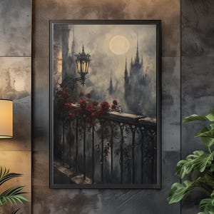 May include: A framed wall art print depicting a dark, atmospheric balcony scene at night. The image features a wrought iron railing adorned with vibrant red roses, a glowing street lamp, a full moon, and distant gothic castle silhouettes.