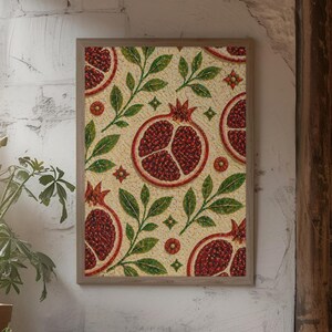 May include: Framed art print with a pomegranate design. The artwork displays a repeating pattern of halved pomegranates, green leaves, and small red flowers on a beige background. The print is in a light brown wooden frame.