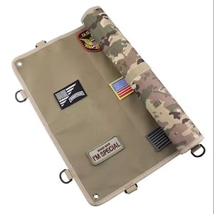 May include: A tan canvas roll-up organiser with several patches, including a U.S. military emblem, an American flag, and the text "MAMA SAYS I'M SPECIAL." The rolled section has a camouflage pattern.