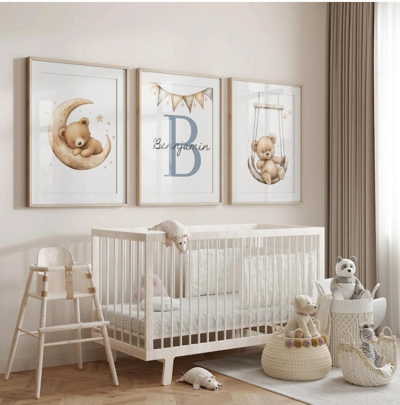 May include: Three framed nursery art prints featuring watercolor teddy bears. One shows a bear on a crescent moon, another has a large blue letter "B" with the name "Benjamin", and the third shows a bear on a swing. A white crib and stuffed animals are in the foreground.