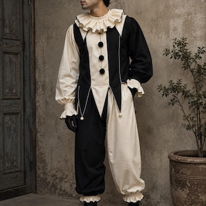 Könnte beinhalten: Ein schwarz-cremefarbener Jumpsuit mit Rüschenkragen, langen Ärmeln mit Rüschenbündchen und drei schwarzen Bommeln auf der Vorderseite. Das Kleidungsstück hat ein zweifarbiges Design mit abwechselnden schwarzen und cremefarbenen Bahnen und schwarzen Stiefeln.