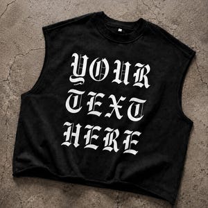 Può includere: Una t-shirt nera senza maniche con orlo a taglio vivo e girocollo. La parte anteriore presenta la scritta "YOUR TEXT HERE" stampata in un grande carattere bianco in stile gotico. Il capo è realizzato in un tessuto nero a tinta unita.