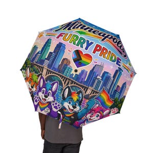 Op de afbeelding: Een meerkleurige paraplu met de tekst Minneapolis FURRY PRIDE, een stadssilhouet, een hartvormige pride-vlag en vier antropomorfe dierenfiguren. Eén figuur houdt een regenboogvlag vast en pootafdrukken sieren de randen van de paraplu.