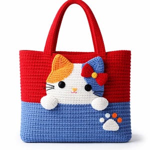 Op de afbeelding: Handgemaakte gehaakte draagtas met een kattenontwerp. De tas is rood en blauw, met een witte kattenkop, oranje en blauwe oren en een blauwe strik. De tas heeft een pootafdruk op de voorkant.