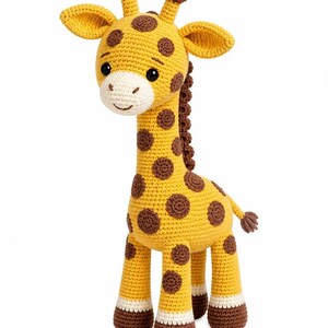 Op de afbeelding: Een gehaakt giraffespeeltje met een geel lichaam met bruine vlekken, een cr&egrave;mekleurige snuit en donkerbruine hoeven. De giraffe heeft twee kleine hoorntjes op het hoofd, grote zwarte ogen, een geborduurde glimlach en donkerbruine manen op de nek.