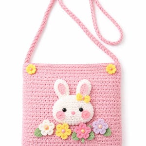 May include: A pink crochet crossbody bag featuring a white bunny face with a yellow bow and floral accents. The bag has a braided strap and is decorated with yellow and other colorful flowers.