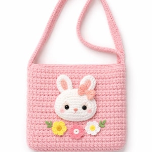 May include: A pink crochet shoulder bag with a white bunny face, pink bow, and floral details. The bag has a rectangular shape and a matching pink strap. The bag is approximately 20 cm wide and 23 cm tall.
