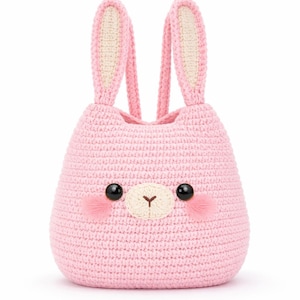 Peut inclure: Un sac en forme de lapin rose crocheté, avec un visage mignon, des yeux noirs et des joues roses. Le sac a de longues oreilles dressées avec un intérieur crème. Le sac est conçu pour ressembler à un lapin.