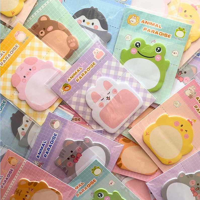 May include: A collection of colorful animal-shaped sticky notes, including a bear, penguin, pig, rabbit, frog, and cat. Each note is packaged with the words "ANIMAL PARADISE" printed on the packaging.