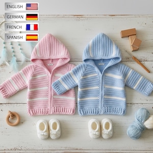 May include: Two crocheted hooded cardigans, one in light pink and one in light blue, both featuring horizontal white stripes. Each cardigan is paired with a matching pair of white crocheted booties, displayed alongside a wooden ring and yarn.