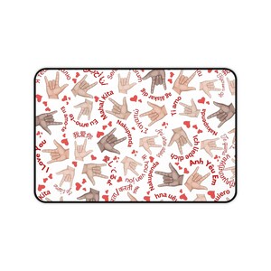 Puede incluir: Alfombrilla de ratón rectangular blanca con un patrón de gestos de manos en diferentes tonos de piel, deletreando "Te amo" en lenguaje de señas. Corazones rojos y frases en varios idiomas están presentes.