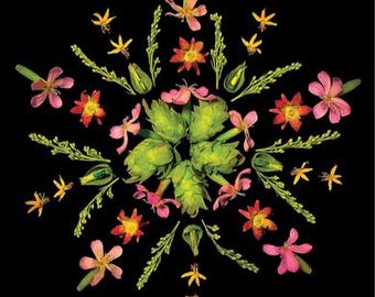 Op de afbeelding: Een symmetrische bloemstuk op een zwarte achtergrond. Het ontwerp toont een centrale cluster van groene artisjokken omringd door roze, oranje en gele bloemen en groene takjes. De algehele compositie is een cirkelvormig patroon.