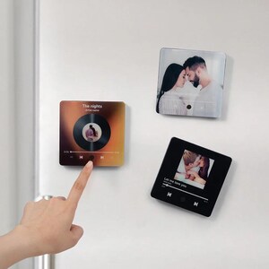 May include: Three square-shaped magnets with personalized photo prints. One features a couple, another a vinyl record design, and the third a photo with the text "Let me love you". The magnets are displayed on a white surface.