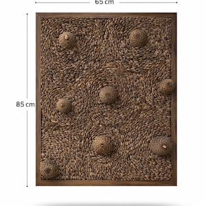 May include: A rectangular wall art piece, 65 cm x 85 cm, with a wooden frame. The artwork features a textured surface of small, oval-shaped elements in shades of brown, with several spherical, textured accents.