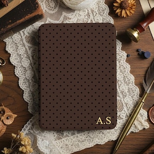Puede incluir: Un cuaderno marrón con lunares y las iniciales doradas "A.S" sobre una superficie de madera. El cuaderno está rodeado de objetos vintage, como un reloj de bolsillo, una pluma y un sello de cera, creando una estética clásica y antigua.