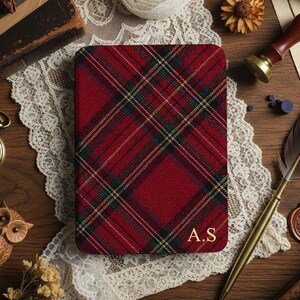 Peut inclure: Un carnet à carreaux rouges avec les initiales dorées "A.S" sur la couverture. Le carnet est entouré d'objets vintage, dont une montre de poche, une plume et un sceau de cire, sur une surface en bois.