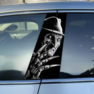 Op de afbeelding: Een zwart-witte vinyl autosticker aangebracht op de verticale stijl tussen de ramen, met een gedetailleerde illustratie van een personage met een fedora-hoed en lange, scherpe metalen messen aan de vingers van één hand.
