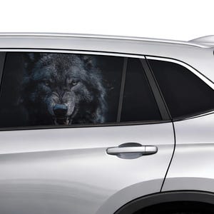 Op de afbeelding: Een zilveren SUV met een raamsticker met een close-up van een grommende zwarte wolf. De vacht van de wolf is donker en getextureerd, met zichtbare tanden en intense ogen. De deurklink en het raamkozijn van de auto zijn zichtbaar.