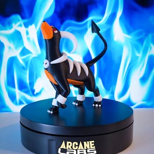 Könnte beinhalten: Eine schwarz-orange-weiße Hunde-Figur mit geschwungenen Hörnern und einem spitzen Schwanz, die auf einem schwarzen, runden Sockel steht, auf dessen Vorderseite der Text ARCANE LABS in weißen und gelben Buchstaben aufgedruckt ist.