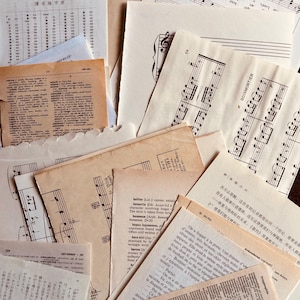 May include: A collection of vintage paper ephemera, including sheet music, dictionary pages, and text in multiple languages. The papers are various sizes and shades of cream and tan, creating a layered, textured composition.