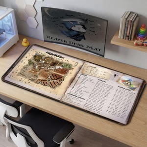 May include: A large desk mat with a map and notes design. The mat features a detailed map labeled "Ragnarok" and a section with handwritten notes. A curved monitor displays a cartoon reaper bunny. The mat is on a wooden desk.