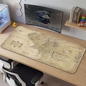 Puede incluir: Una alfombrilla de escritorio rectangular con un mapa detallado de la Tierra Media en tonos sepia. La alfombrilla tiene una superficie texturizada e incluye el texto "Middle Earth" y "The Sundering Seas".