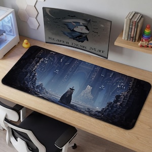 Könnte beinhalten: Rechteckige Schreibtischunterlage mit einer düsteren Fantasy-Szene. Sie zeigt eine Figur in einem Umhang und Hut. Die Unterlage hat einen schwarzen Rand und der Text "REAPER DESK MAT" ist auf einem Monitor zu sehen. Eine Gummiente liegt auf dem Schreibtisch.