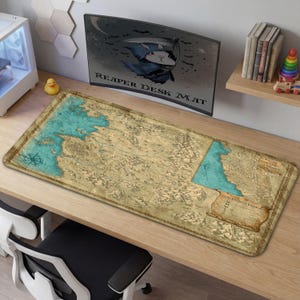 May include: A rectangular desk mat featuring a detailed map design with teal and tan colors. The mat has a distressed, vintage aesthetic. The words "Reaper Desk Mat" are printed on the monitor in the background.