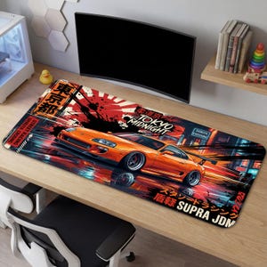 Könnte beinhalten: Orangefarbenes Supra JDM-Mauspad mit einem Rennwagen-Motiv in einer nächtlichen Stadt. Das Mauspad hat japanischen Text und die Wörter "Tokyo Midnight" und "Shibuya Crossing".