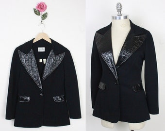 May include: A black blazer with a black patent leather collar and pockets. The blazer has a single button closure.