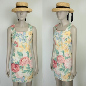 May include: A sleeveless, yellow floral print dress with a square neckline. The dress is fitted and has a short length. The model is wearing a straw hat with a black ribbon.