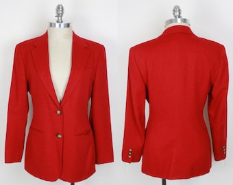 May include: A vibrant red blazer with a classic tailored design. The jacket features a notched lapel, two front pockets, and two brown buttons. The sleeves have three matching buttons. The blazer is displayed on a mannequin, showcasing both the front and back.