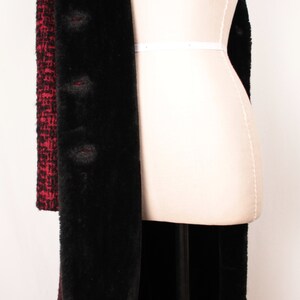 May include: A long black and red coat with a faux fur lining. The coat is on a white dress form.