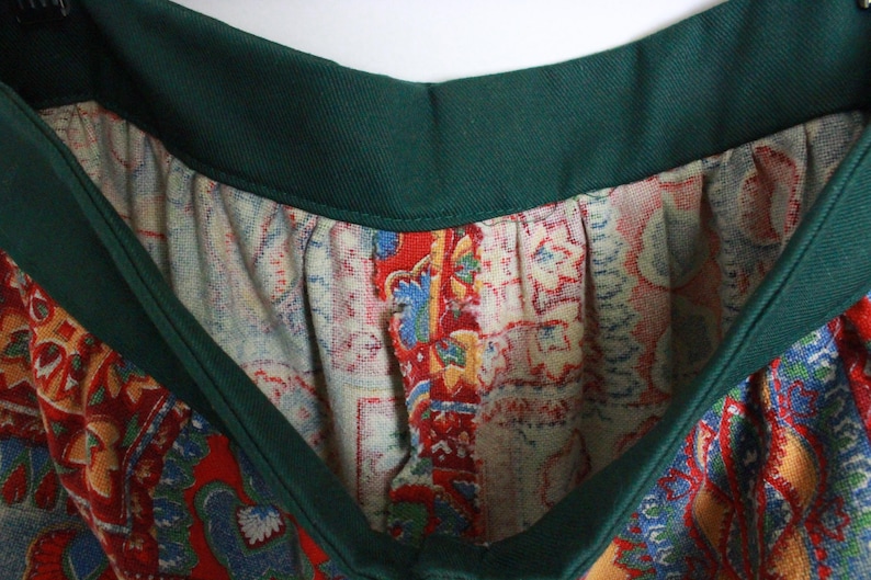 K&ouml;nnte beinhalten: Ein gr&uuml;n-roter gemusterter Rock mit gr&uuml;nem Bund. Der Rock hat ein Paisley-Muster.