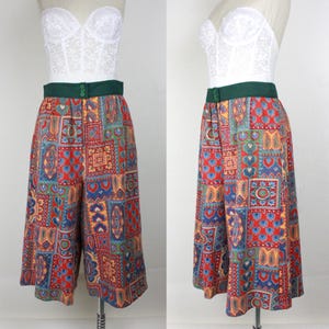 K&ouml;nnte beinhalten: Eine weite, kurze Hose mit einem bunten Patchwork-Muster. Die Hose hat einen gr&uuml;nen Bund und einen Knopfverschluss. Die Hose befindet sich auf einem wei&szlig;en Mannequin.