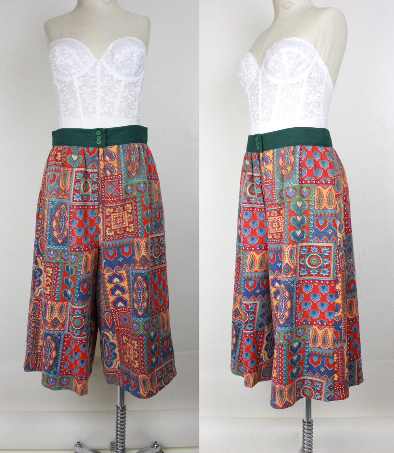 K&ouml;nnte beinhalten: Eine weite, kurze Hose mit einem bunten Patchwork-Muster. Die Hose hat einen gr&uuml;nen Bund und einen Knopfverschluss. Die Hose befindet sich auf einem wei&szlig;en Mannequin.