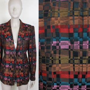 Puede incluir: Una chaqueta de color marrón, negro, rojo, rosa y azul con un patrón de cuadros y cierre de un solo botón.