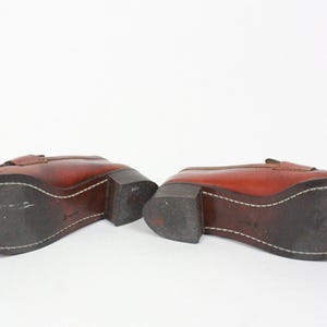 May include: A pair of brown leather loafers with a stitched seam around the sole. The loafers have a low heel and a pointed toe.