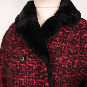 May include: A red and black tweed coat with a black faux fur collar. The coat has a double breasted closure with two large buttons.