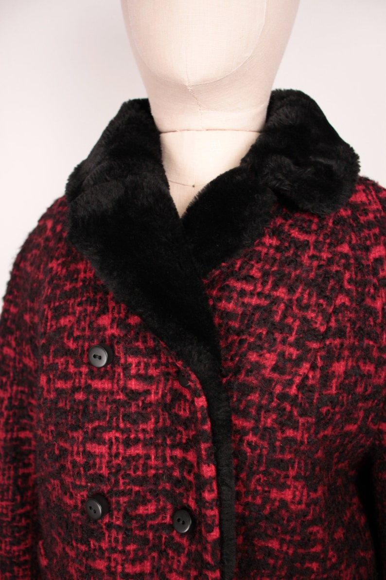 May include: A red and black tweed coat with a black faux fur collar. The coat has a double breasted closure with two large buttons.
