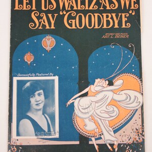 May include: A vintage sheet music cover with a dark green background and a title that reads "Let Us Waltz As We Say 'Goodbye'" in orange lettering. The cover features a couple dancing in a stylized art deco design with a blue and orange background. The music is by Art L. Beiner and features Lucille Cinde.